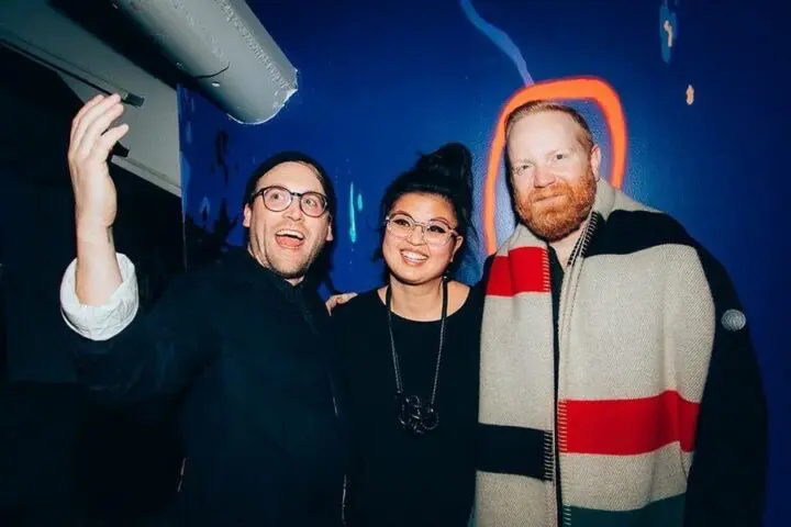 Michael Ellsworth, Trish Chua, and Corey Gutch smiling in front of a colorful wall, one...