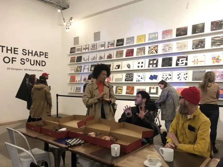People enjoying coffee and examining creative record covers at The Shape of Sound galle...