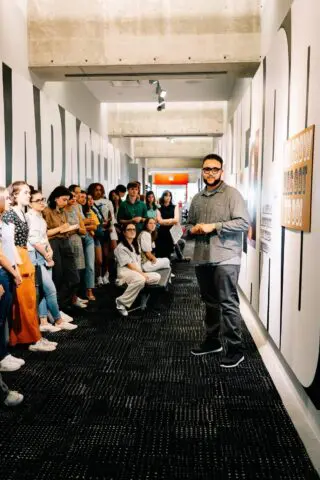Group of students attentively listening to a speaker in a modern hallway presentation.