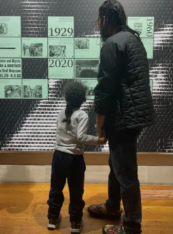 A man and child view a historical timeline display in a museum, highlighting significan...