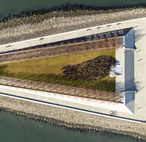 Aerial view of a large graphic installation of a face on a riverside walkway, surrounde...