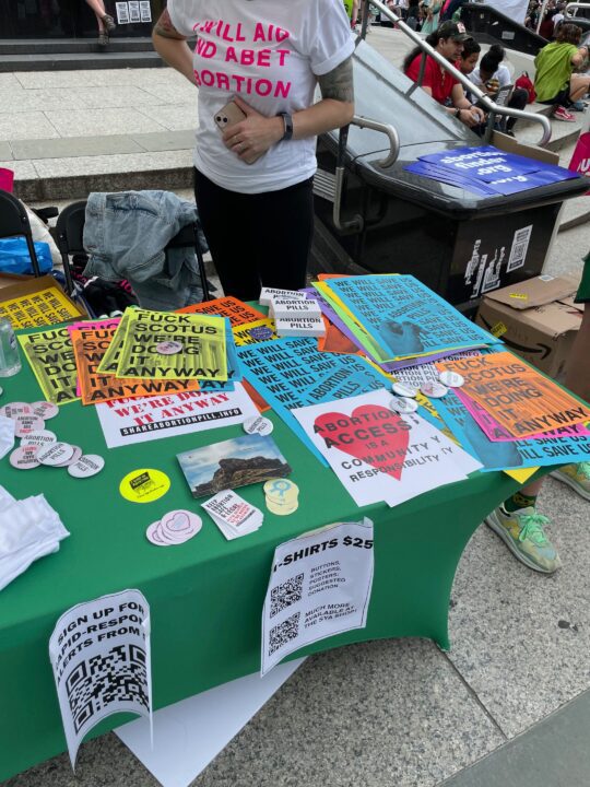 Activist table with pro-abortion rights posters, shirts, and informational materials at...