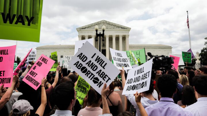 Protesters with I Will Aid and Abet Abortion signs gather at the Supreme Court, demonst...