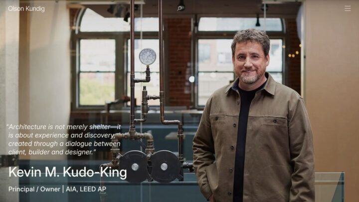 A man stands beside industrial pipes in an architecturally designed room, emphasizing c...