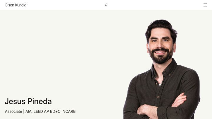 Portrait of a smiling man in a dark shirt with arms crossed, showcasing professional cr...