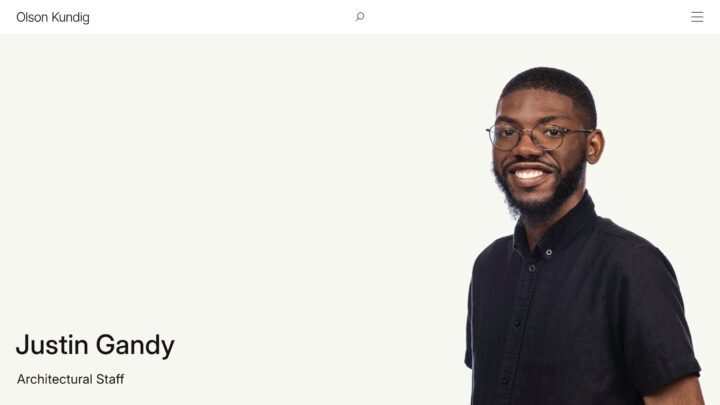 Smiling man in glasses and black shirt on plain background, labeled as architectural st...