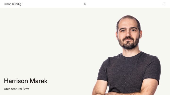 Man in a gray t-shirt, standing with arms crossed against a light background, part of a...