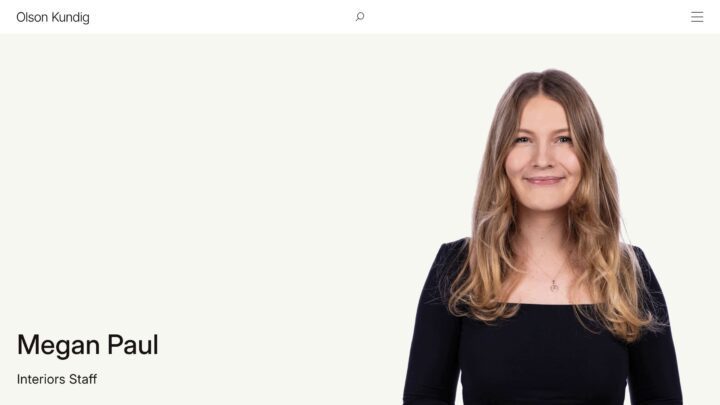 Smiling woman with long hair in a black top, labeled as interiors staff, on a professio...