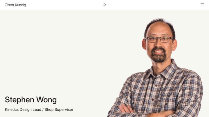 Person in plaid shirt smiling with arms crossed, labeled as Kinetics Design Lead / Shop...