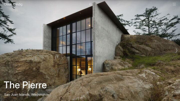 Modern house built into a rocky hillside, featuring large glass windows, located in San...