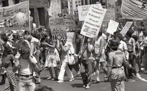People marching with signs for human and gay rights in a protest, advocating for equality and justice.