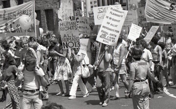 People marching with signs for human and gay rights in a protest, advocating for equali...