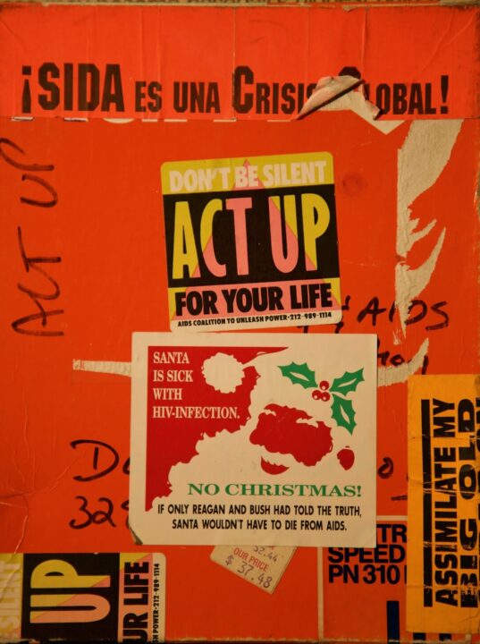 Bold red protest stickers addressing the global AIDS crisis with messages of activism a...