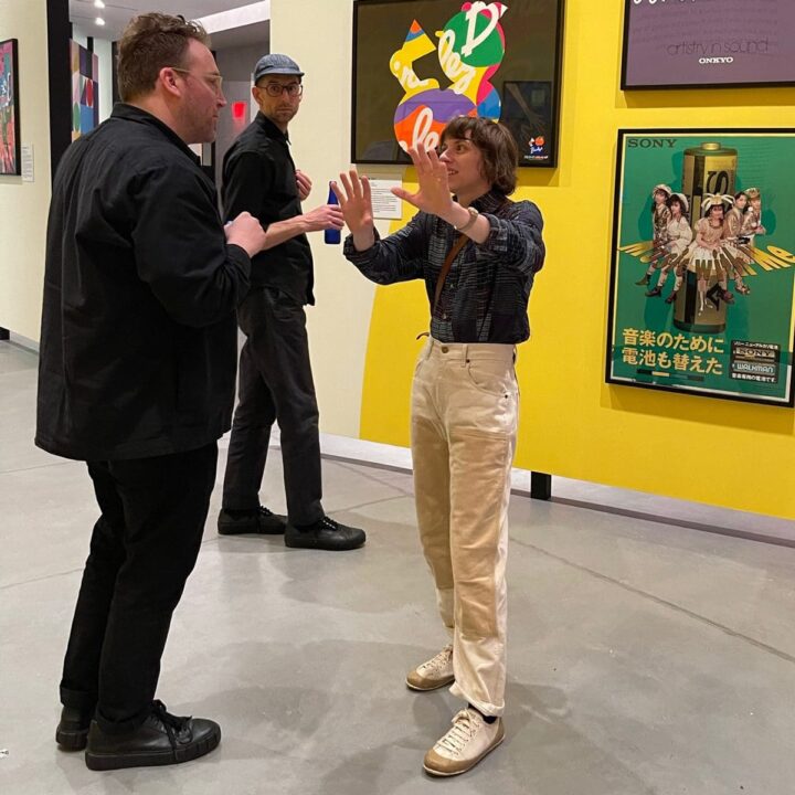 Molly Derse and Michael Ellsworth engaged in animated conversation at Posterhouse gallery in NYC, with colorful artwork on the walls.
