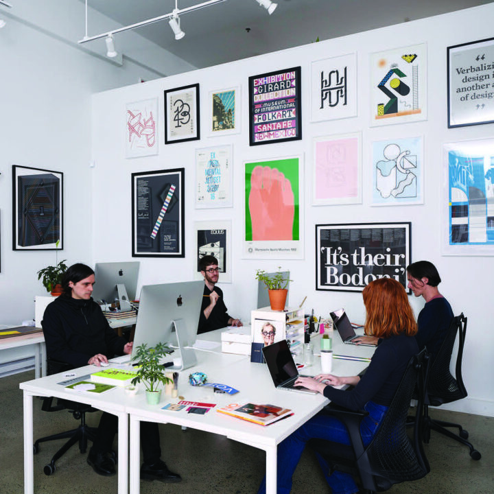 Civilization at our former office/gallery space working at desks, surrounded by modern art and typography posters on white walls.