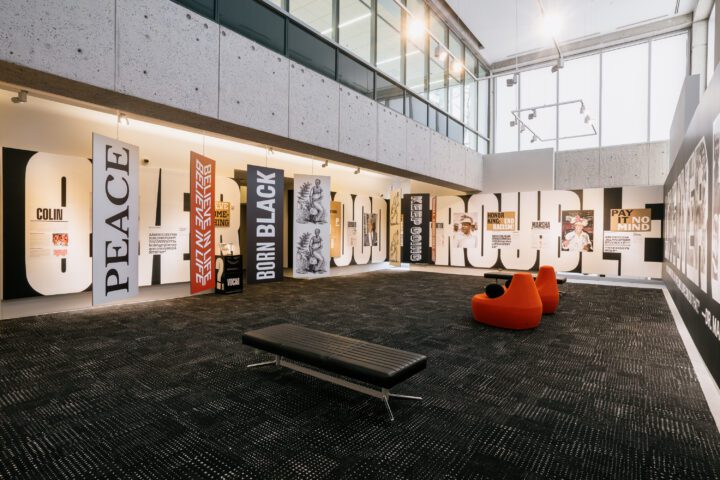 Contemporary gallery exhibit with bold typography and social justice themes, featuring ...