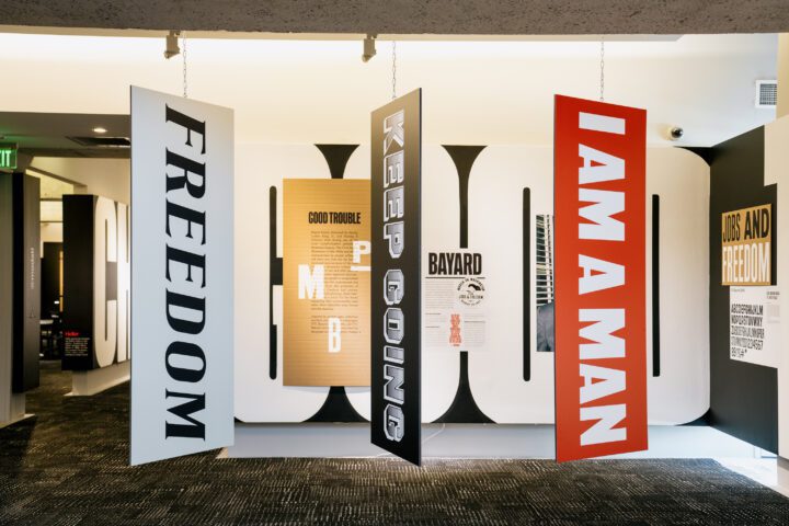 Hanging signs with messages FREEDOM, KEEP GOING, and I AM A MAN in a modern museum exhi...