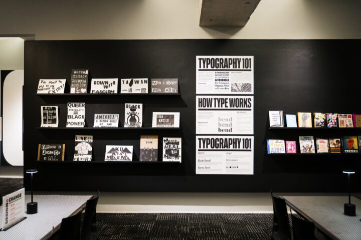 Typography and design exhibit wall with books and posters, showcasing diverse themes an...
