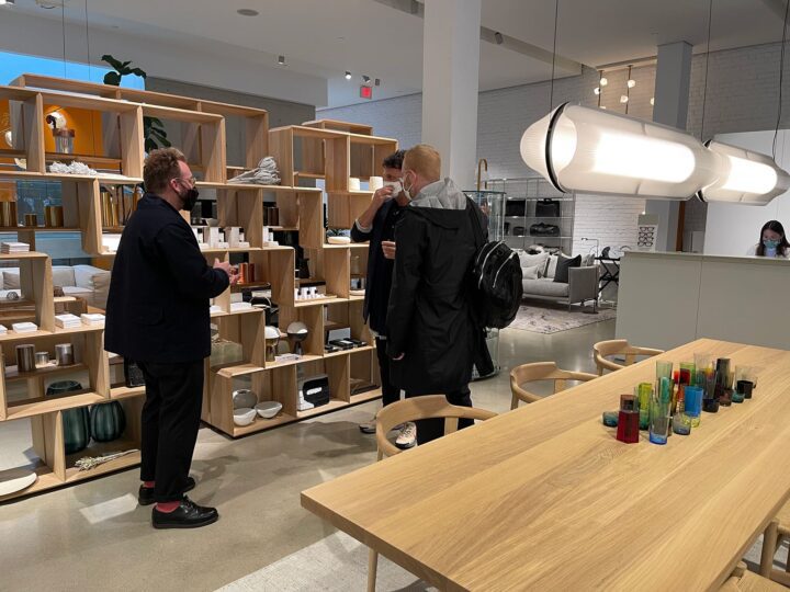 Modern store interior with people discussing near wooden shelves displaying various hom...