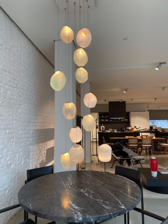 Modern dining room with hanging pendant lights over a round marble table, set against a...