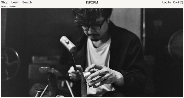 Artisan crafting metal with a hammer, focusing intently in a dimly lit workshop.