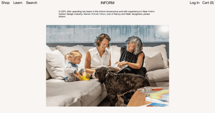 Two women sit on a couch with a small child and a dog, looking at a book together in a ...