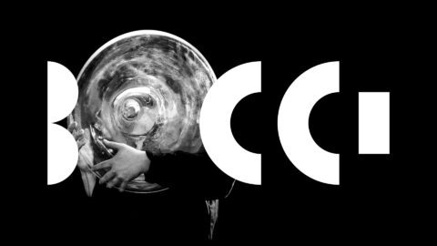 Black and white image of a person holding a tuba, framed by bold white letters BOCCI on a black background.