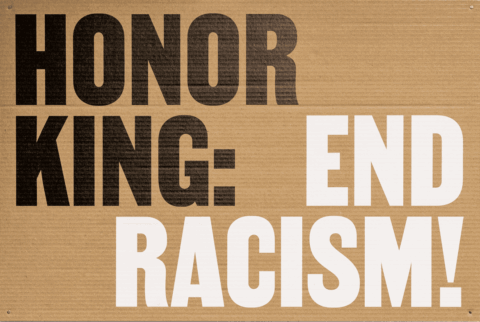 Protest sign with 'Honor King: End Racism!' in bold letters on corrugated cardboard bac...