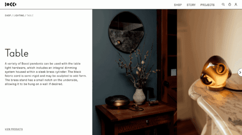 Modern interior with round mirror, decorative vase, and Bocci table lamp on a wooden and marble surface. Elegant lighting decor.