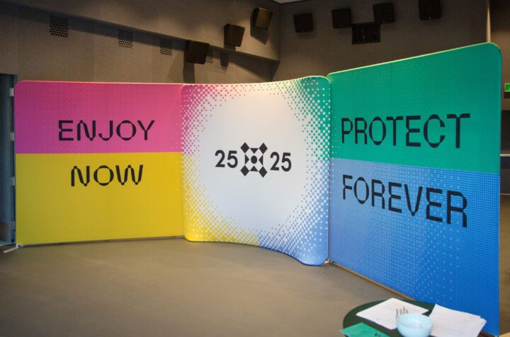 Colorful wall display with Enjoy Now 25x25 Protect Forever emphasizing sustainability m...