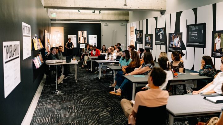 Audience at a the Characters Exhibition design and typography workshop in a modern classroom, featuring black walls with inspirational posters and attentive participants at the Museum of Design Atlanta..