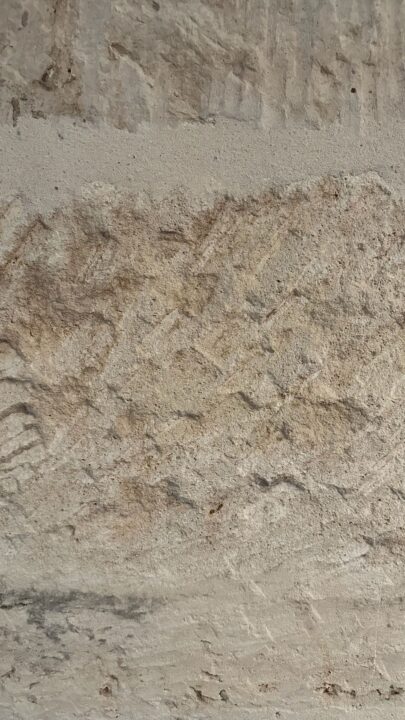 Close-up of textured stone wall surface, showcasing intricate natural patterns and eart...