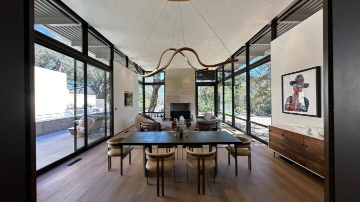 Modern dining room with large windows, unique chandelier, and stylish furniture, offeri...