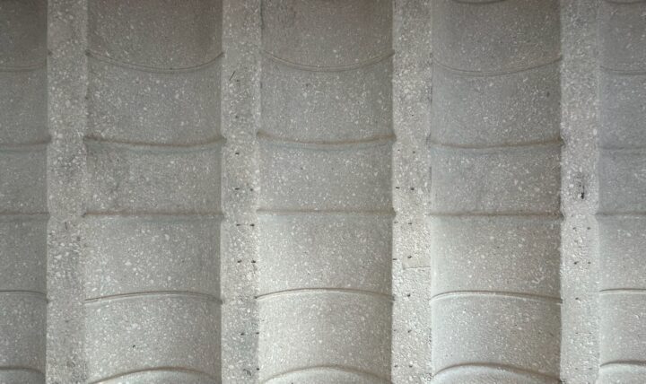 Textured concrete wall with curved, column-like patterns, highlighting architectural de...