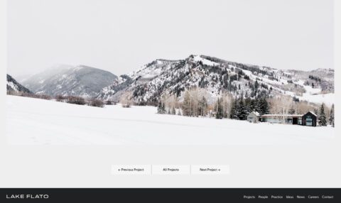Snow-covered mountains with a modern cabin nestled among trees, showcasing a winter landscape.