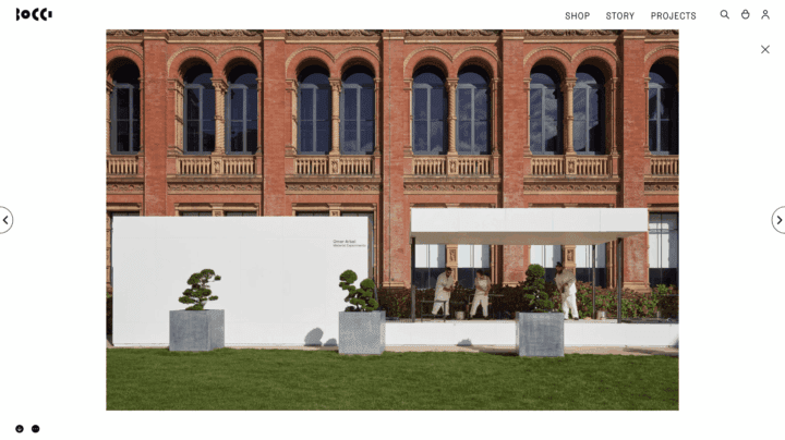 Modern art installation in a historic building with two people interacting, trees in pl...