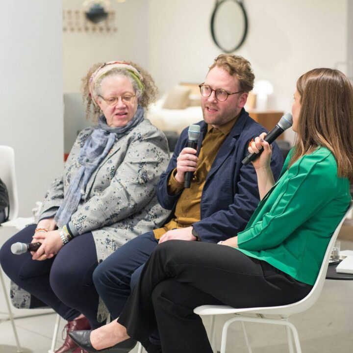 Gail Anderson, Michael Ellsworth, and Elizabeth Gerber engage in a lively panel discussion for the Cooper Hewitt Smithsonian Design Museum National Design Awards in San Francisco, holding microphones, seated in a modern venue.
