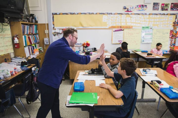 Michael Ellsworth high-fives a student in a lively classroom discussion for the Cooper Hewitt Smithsonian Design Museum National Design Awards in San Francisco, fostering learning and collaboration.