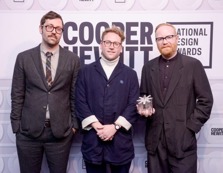 Gabriel Stromberg, Michael Ellsworth, and Corey Gutch in suits pose with the National Design Award trophy at the Cooper Hewitt National Design Awards event.