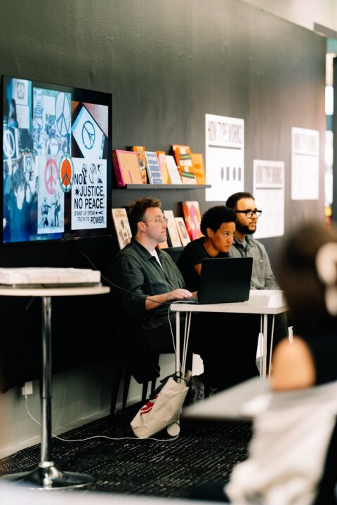 Panel discussion with diverse speakers on social justice, featuring a laptop and protes...