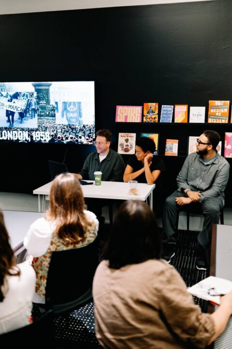 Panel discussion with three people in front of a slideshow about London, 1958. Books di...