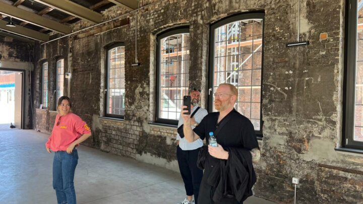 People exploring a rustic industrial space with exposed brick walls and large windows.