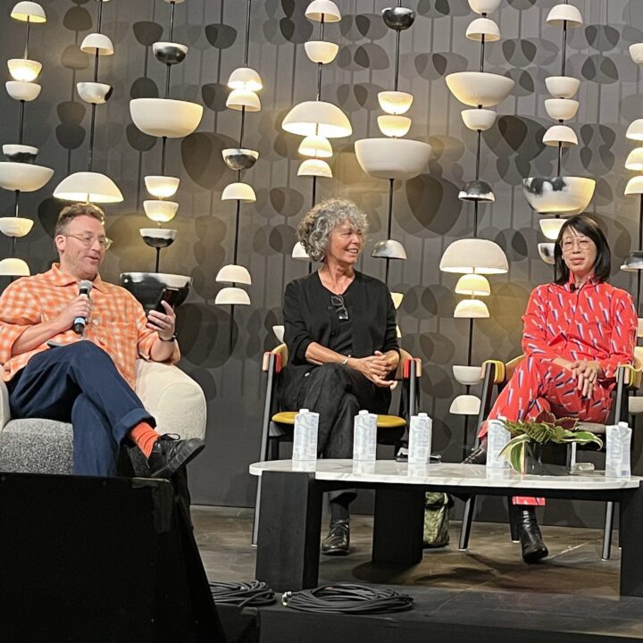 Michael Ellsworth, Nancy Bendtsen, and Ming-Lee Yuan in a panel discussion on stage, at IDS West in Vancouver BC under modern lighting design in background, conference setting.